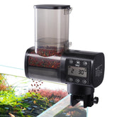 Hygger automatic fish feeder on tank glass shows adjustable feeding schedule for vacations.